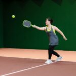 A woman engaging in pickleball on an indoor court, showcasing athletic skill and focus.