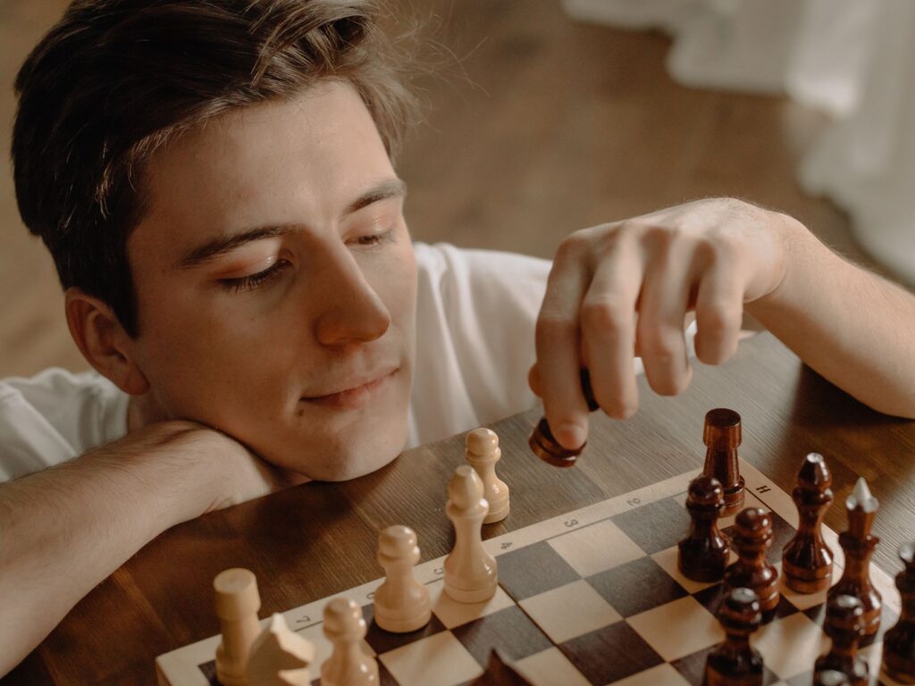 Thoughtful man making a chess move while relaxing at home, focused on strategy.