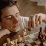 Thoughtful man making a chess move while relaxing at home, focused on strategy.