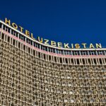 Low angle shot of Hotel Uzbekistan facade against a clear blue sky.