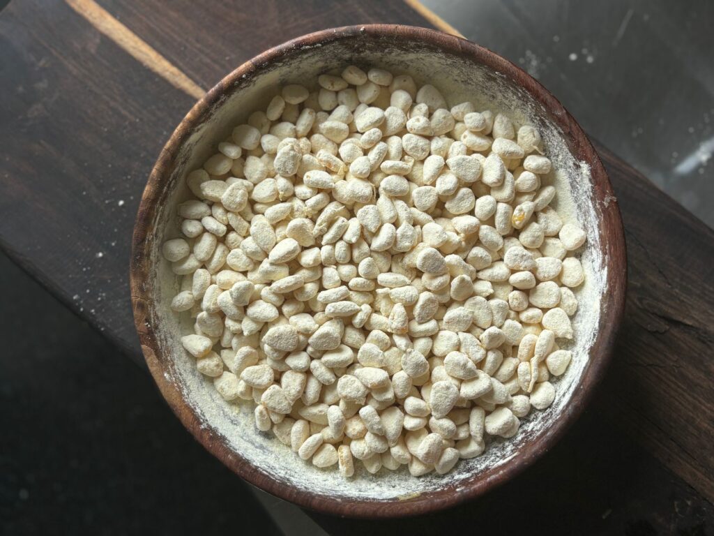 Close-up of a wooden bowl filled with traditional Indian puffed rice on a wooden surface.