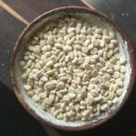Close-up of a wooden bowl filled with traditional Indian puffed rice on a wooden surface.