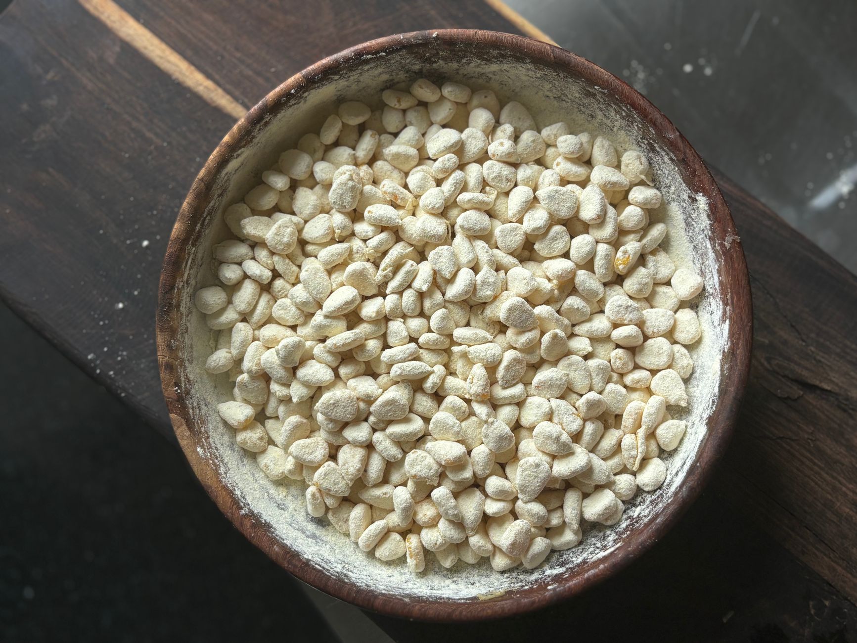 Close-up of a wooden bowl filled with traditional Indian puffed rice on a wooden surface.
