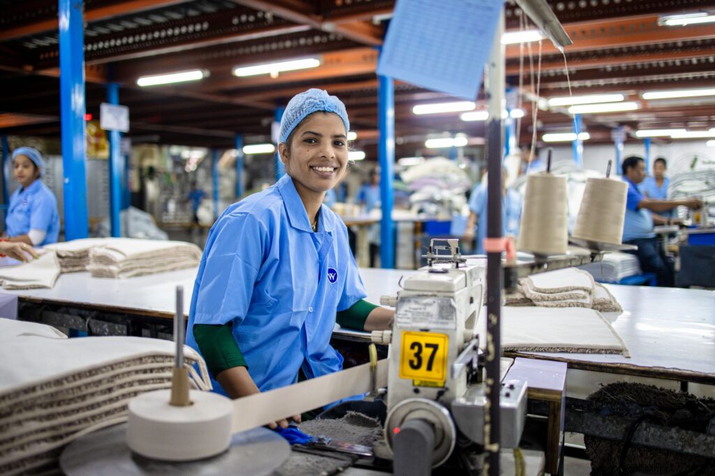 Smiling female textile worker at sewing machine in a modern factory.