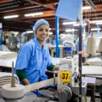 Smiling female textile worker at sewing machine in a modern factory.