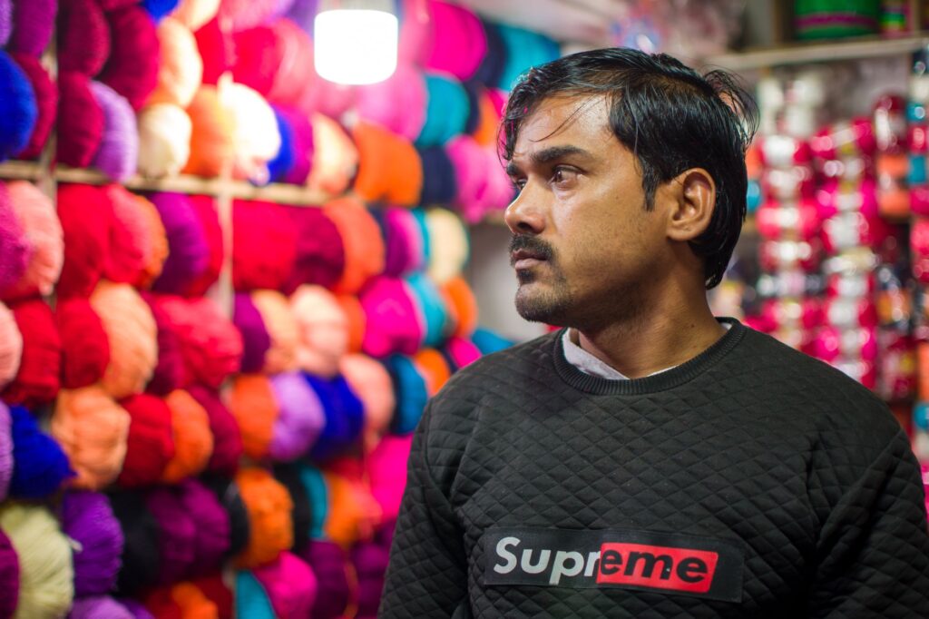 Portrait of a man in a yarn shop surrounded by vibrant colors, creating a unique shopping atmosphere.