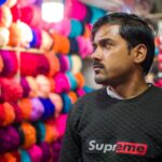 Portrait of a man in a yarn shop surrounded by vibrant colors, creating a unique shopping atmosphere.