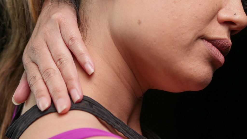 Close-up of a woman holding her neck, indicating pain or discomfort.