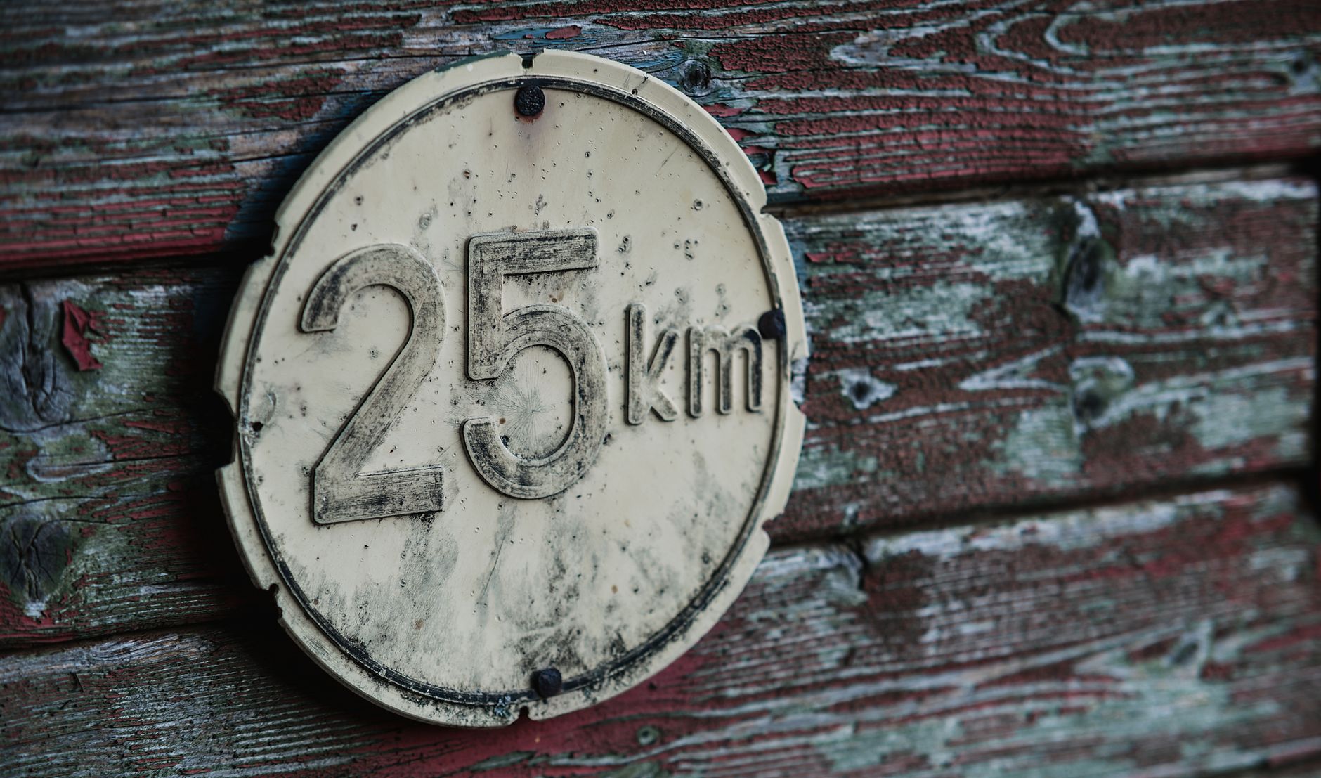 A rustic speed limit sign reading 25 km on a weathered wooden wall, showcasing vintage charm.