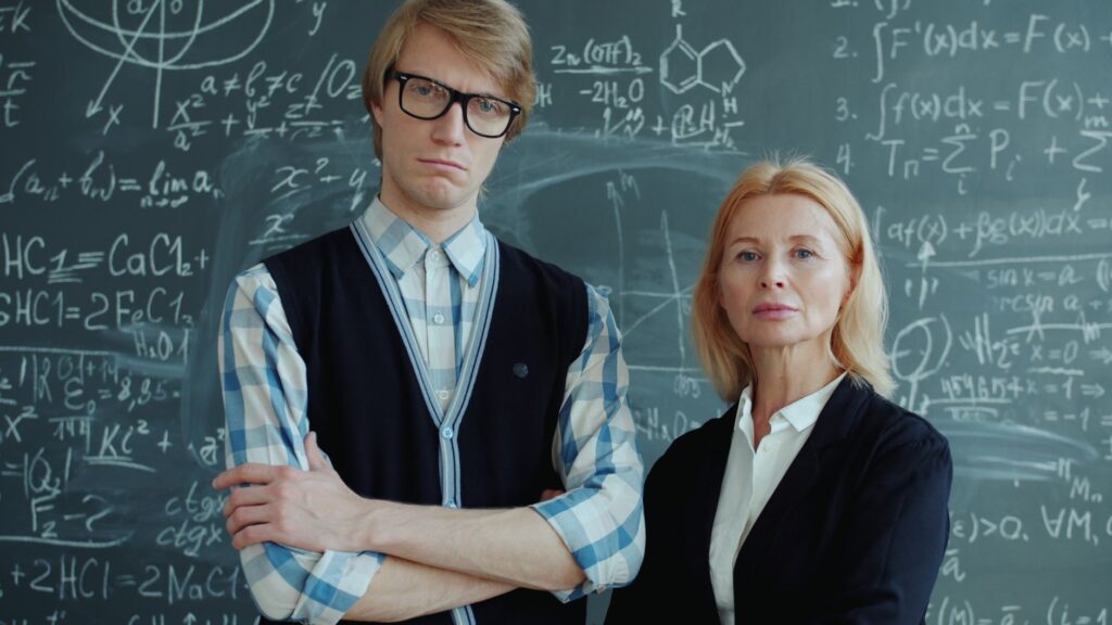 Two teachers standing confidently in front of a blackboard filled with math equations.