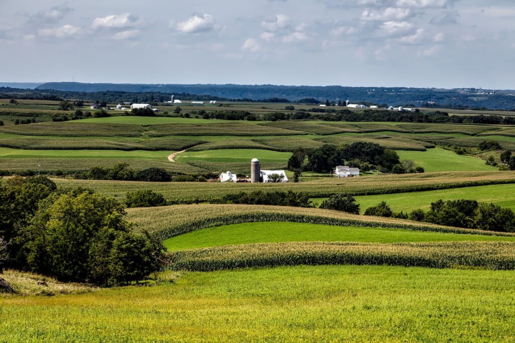 A picturesque view of rolling farmland and fields in Sherrill, Iowa under a clear sky.