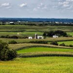 A picturesque view of rolling farmland and fields in Sherrill, Iowa under a clear sky.