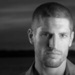 Close-up black and white portrait of a man, emphasizing strong features and mood.
