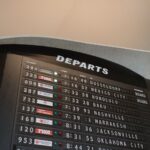 Close-up of airport departure board displaying flight details at JFK Airport, New York.