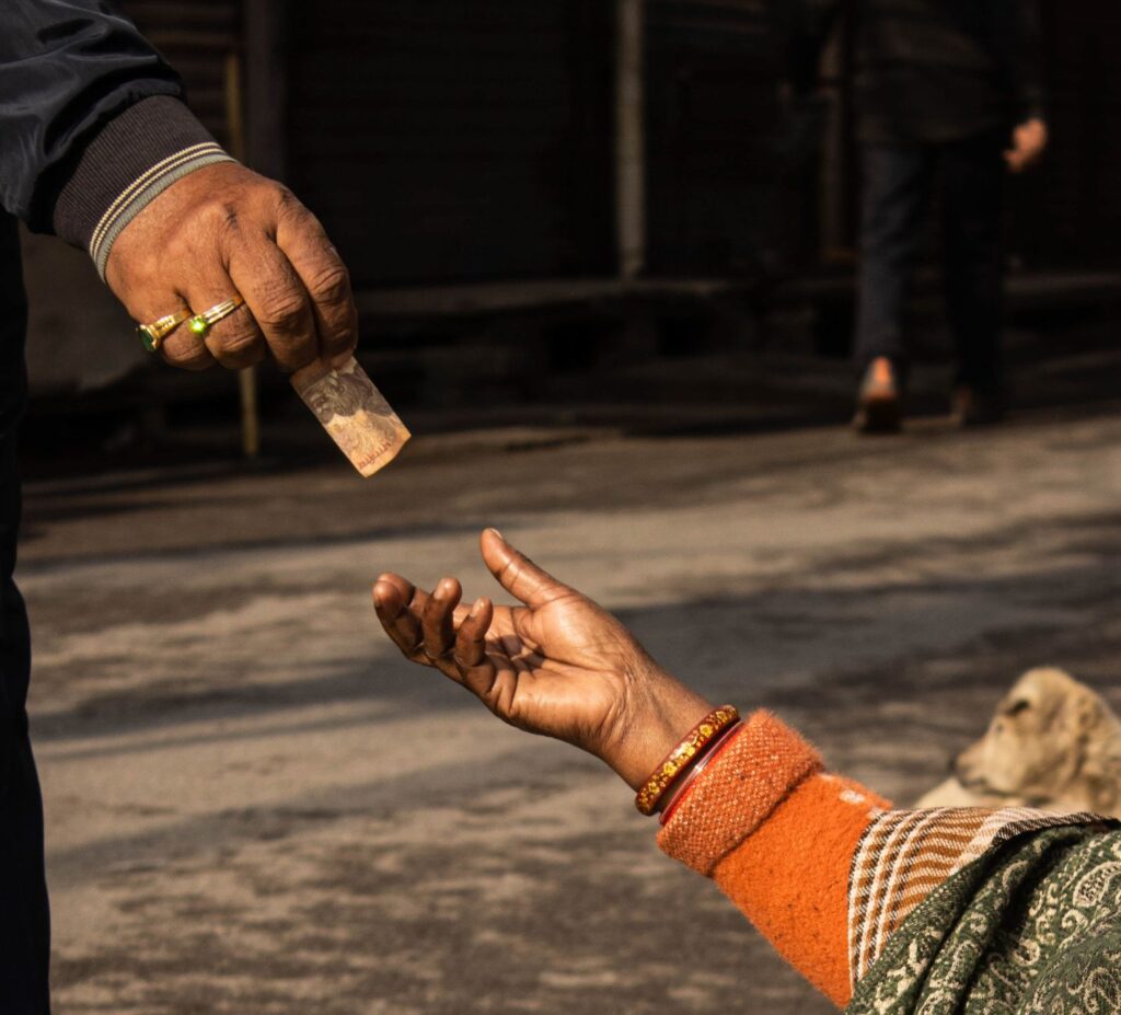 A detailed capture of a street donation with an outstretched hand receiving money.
