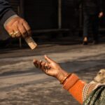 A detailed capture of a street donation with an outstretched hand receiving money.