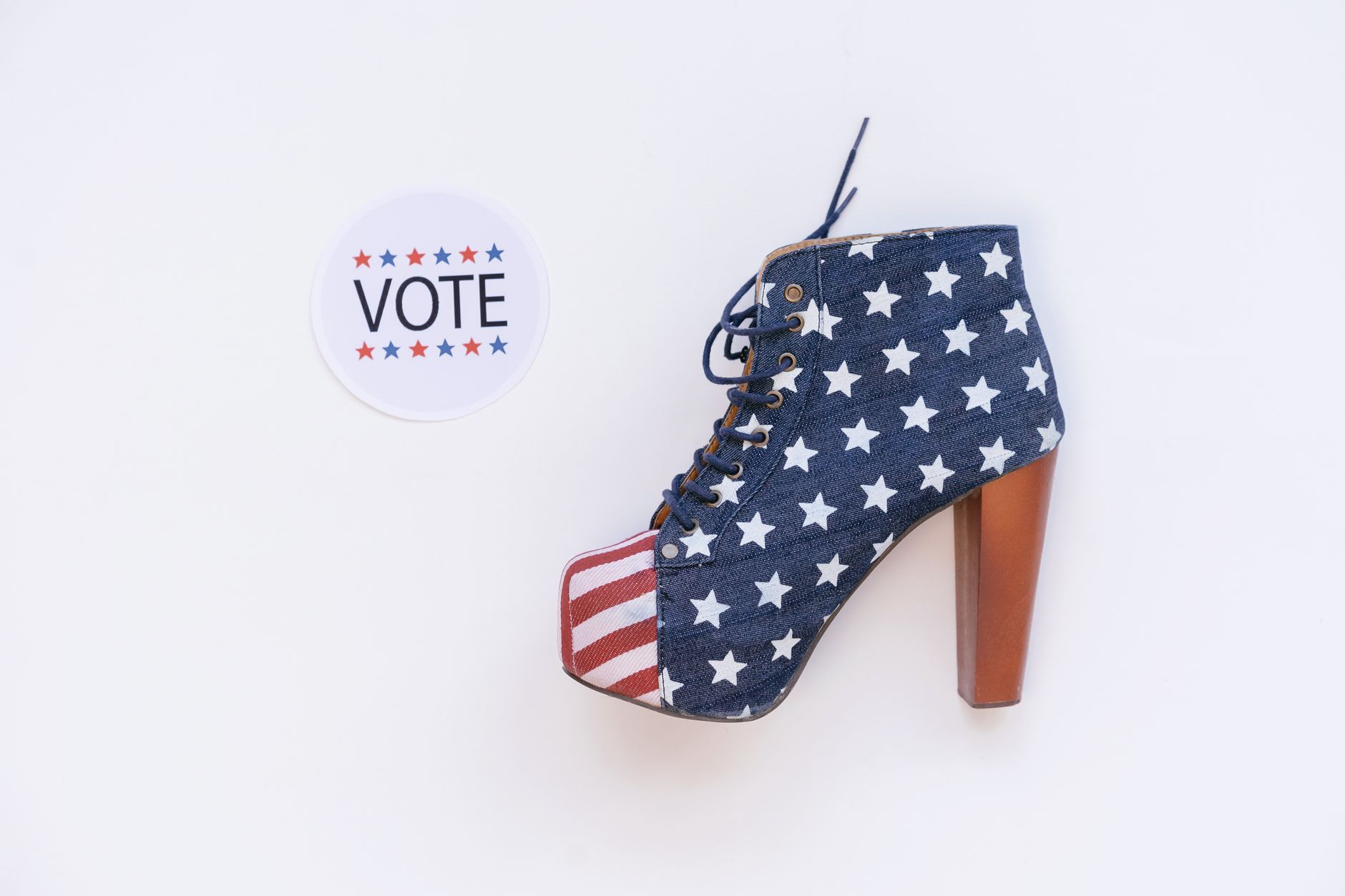 High heel with American flag design beside a voting sticker on white background.