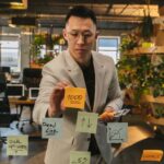 Focused businessman using sticky notes for planning in a green office.