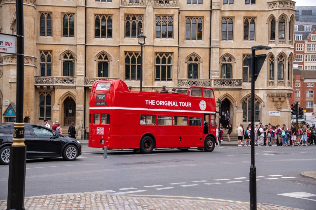 Vintage red double-decker bus offering tours in historic London with people nearby.