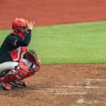 A baseball catcher in full gear giving a signal during a game.