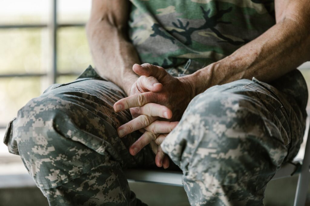 A soldier in camouflage uniform rests with hands folded, depicting calmness.