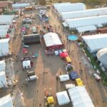 Aerial photograph of a bustling outdoor event with numerous tents, booths, and attendees.