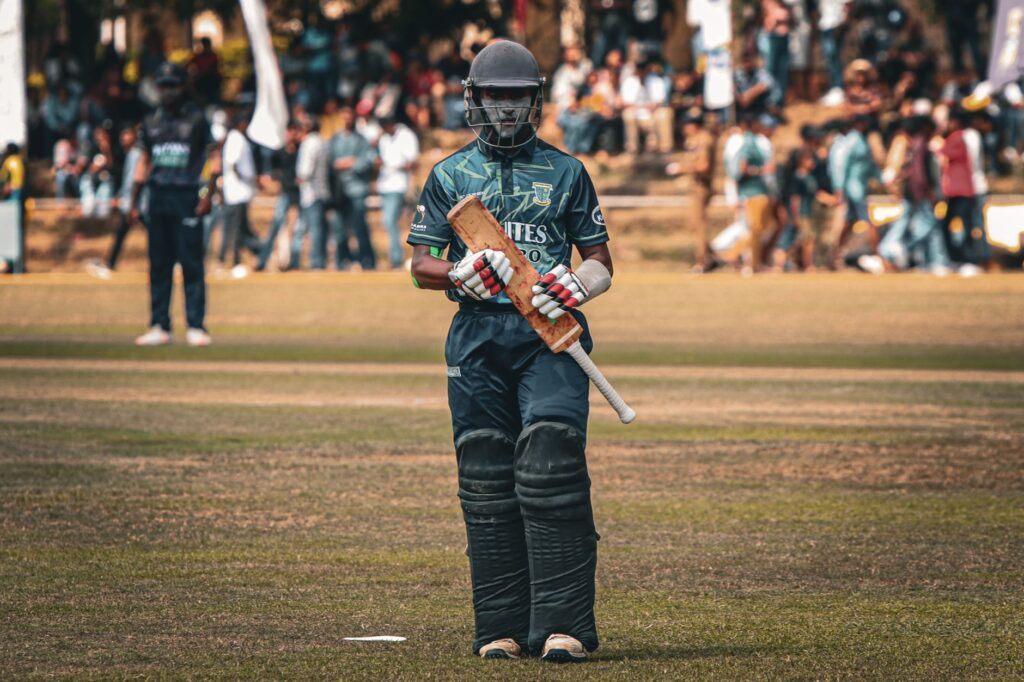 Cricketer with helmet and bat ready to play on the field during a sunny day match.
