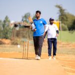 Two men playing cricket outdoors in a sunny field.