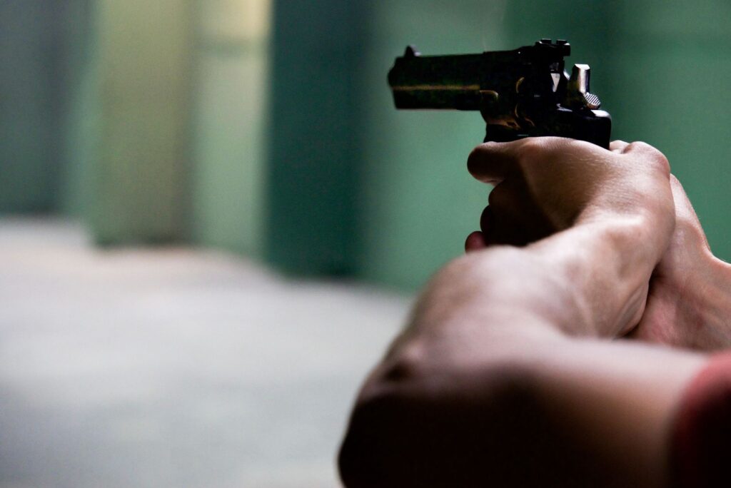 Close-up shot of hands aiming a pistol in an indoor shooting range, emphasizing focus and tension.