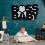 Adorable baby posing in a thematic setup featuring 'Boss Baby' inspired decor and playful props.