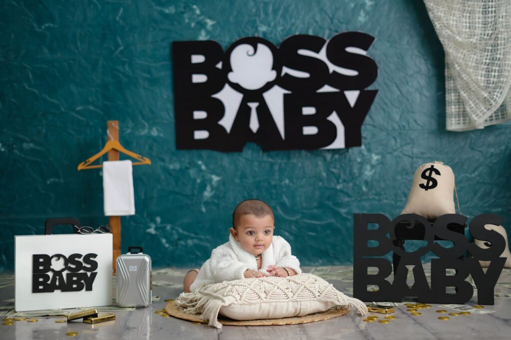 Adorable baby posing in a thematic setup featuring 'Boss Baby' inspired decor and playful props.