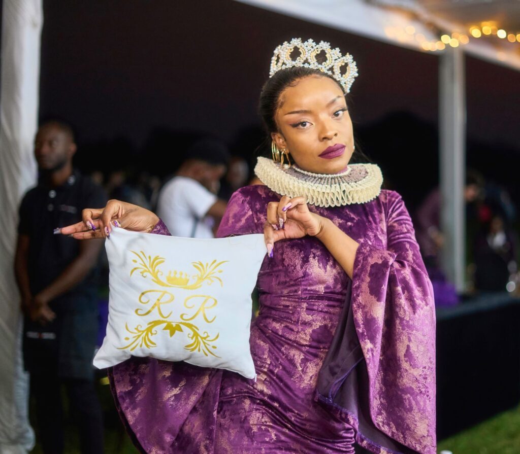A woman in a medieval-inspired costume holding a decorative pillow at an outdoor event.
