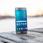 Samsung smartphone placed on a wooden surface outdoors during sunset.