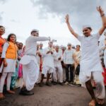 A vibrant Indian street dance with a group of people celebrating in traditional attire outdoors.