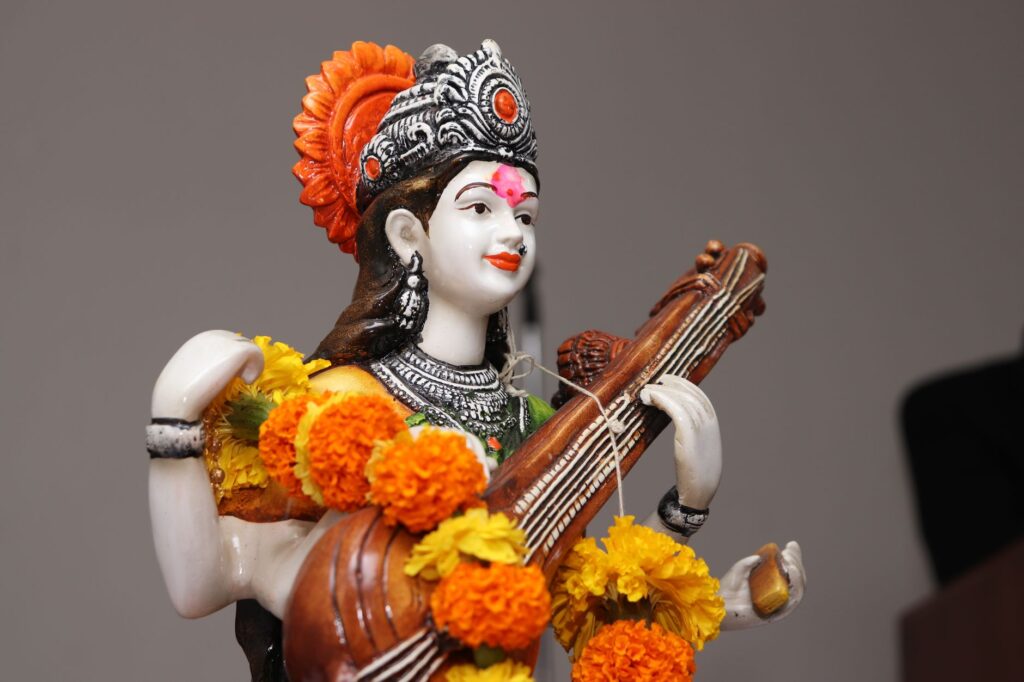Close-up of a Saraswati statue adorned with vibrant marigold flowers, symbolizing wisdom and art.