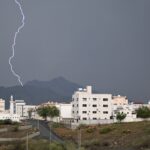 Dramatic lightning bolt over Muhayil city with mountains and storm clouds in Aseer Province, Saudi Arabia.