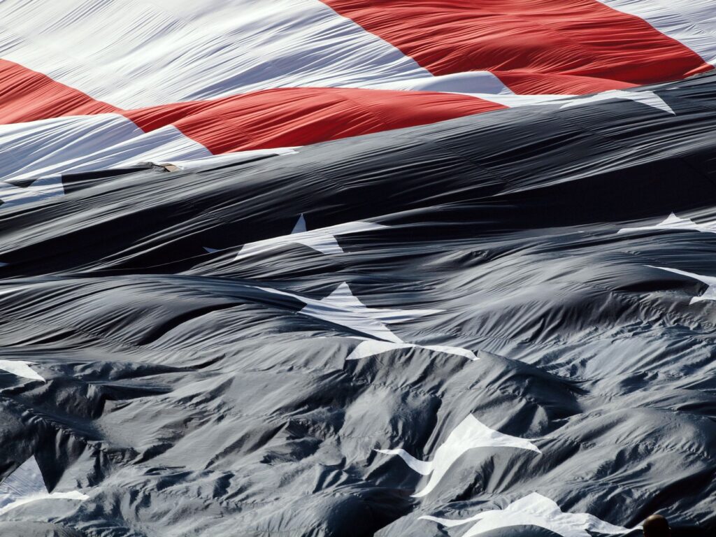 A detailed close-up of the American flag gracefully waving in the wind, showcasing its textures.
