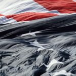 A detailed close-up of the American flag gracefully waving in the wind, showcasing its textures.