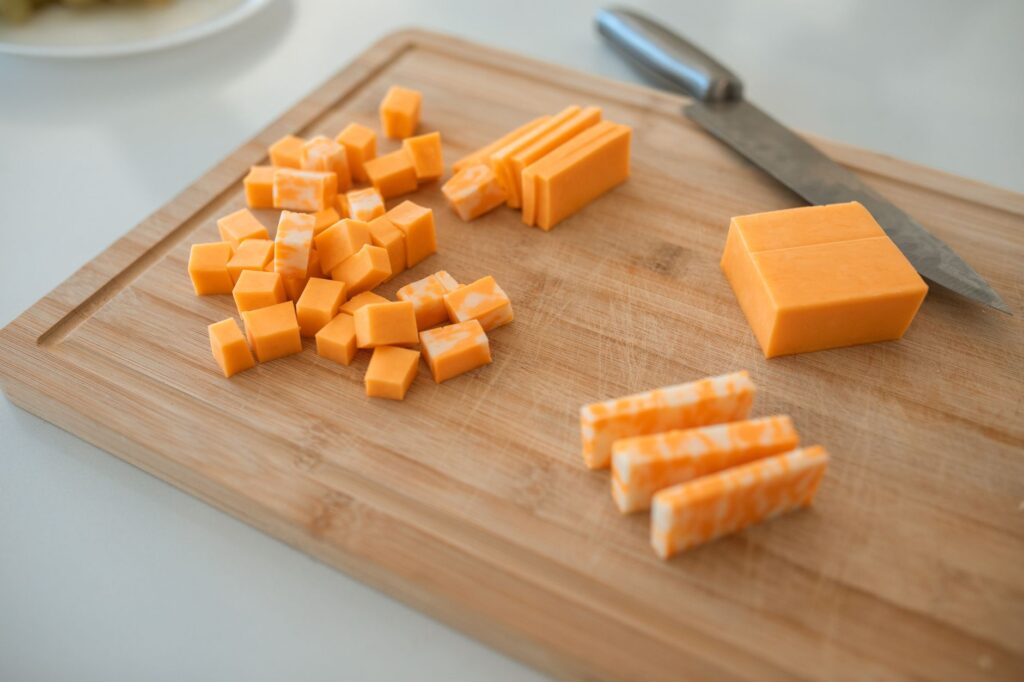 Close-up of cheddar and colby-jack cheese slices on a wooden cutting board with a knife.