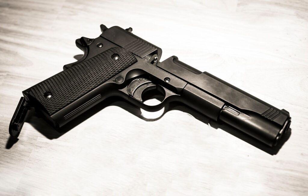 Close-up of a black metal handgun on a light surface, showcasing firearm details.