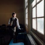 A thoughtful student gazes through a sunlit window in a Buenos Aires classroom.