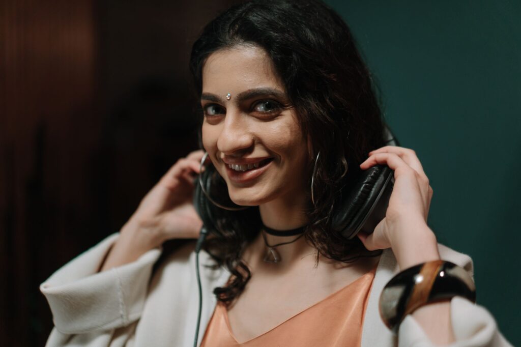 Smiling woman wearing headphones in a music studio, conveying joy and creativity.