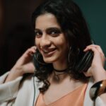 Smiling woman wearing headphones in a music studio, conveying joy and creativity.