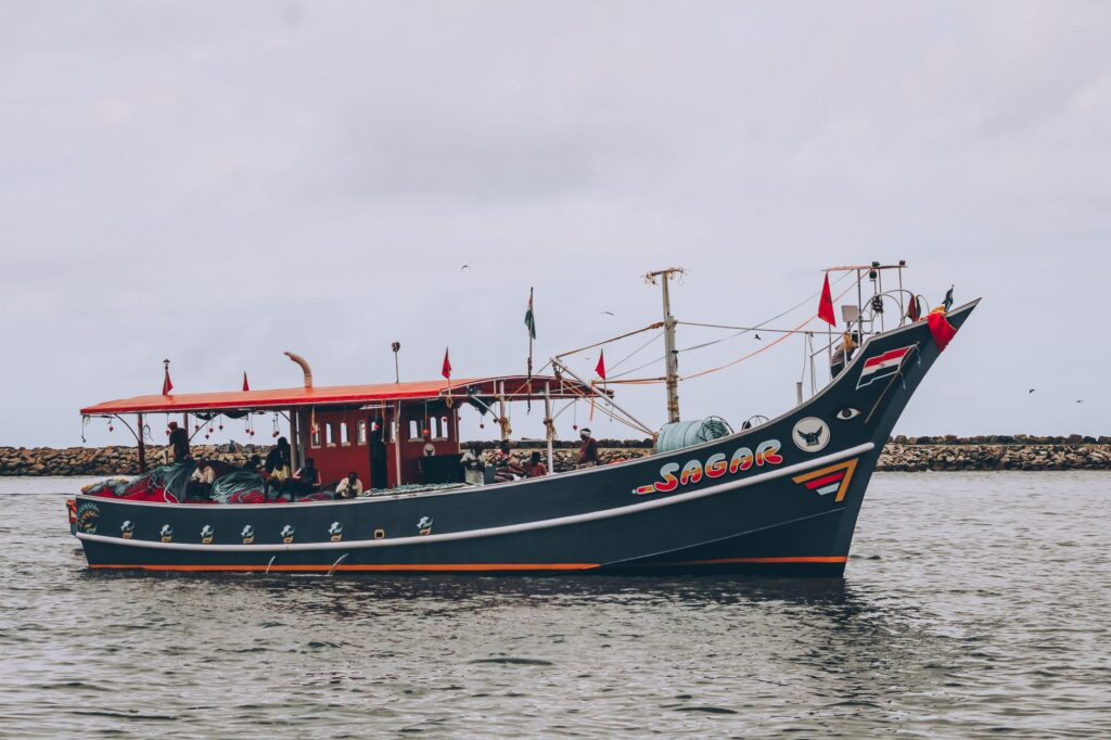 A beautiful Indian fishing boat with colorful flags sails on a cloudy day, showcasing maritime culture.