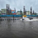 A car navigates through a flooded street in Kolkata, India during monsoon season.