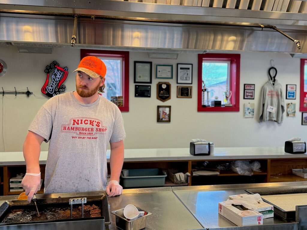 A chef at work in Nick's Hamburger Shop, Brookings, SD, preparing delicious hamburgers.