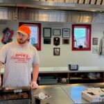 A chef at work in Nick's Hamburger Shop, Brookings, SD, preparing delicious hamburgers.