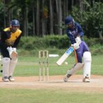 Two cricketers playing an intense match outdoors on a sunny day.