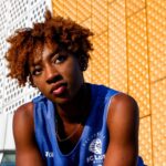 Vibrant portrait of a young woman with afro hairstyle against a modern Berlin backdrop.