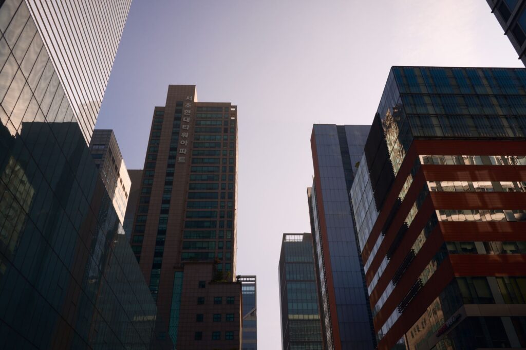 Modern skyscrapers with glass facades reflecting daylight in a bustling cityscape.